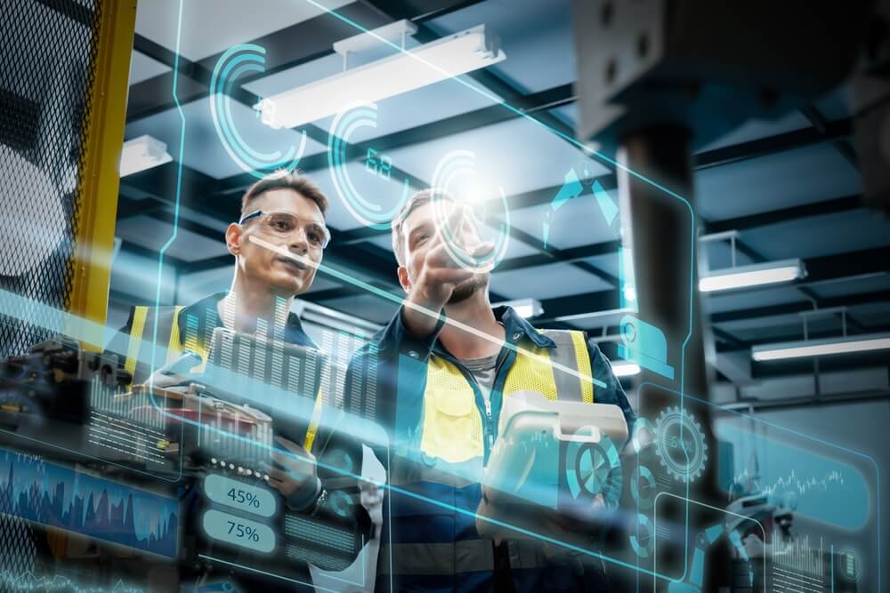 AI (1) Dwóch inżynierów w kamizelkach pracuje z interaktywnym cyfrowym panelem kontroli w fabryce.