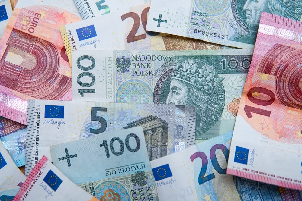Mieszanka banknotów euro i polskich złotych ułożona luźno na stole.