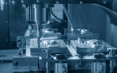 Frezarka CNC obrabiająca metalowe formy na stole maszynowym, z widocznymi detalami i narzędziem